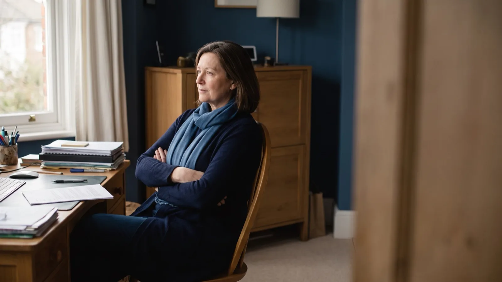 A woman pausing to consider paperwork at a desk